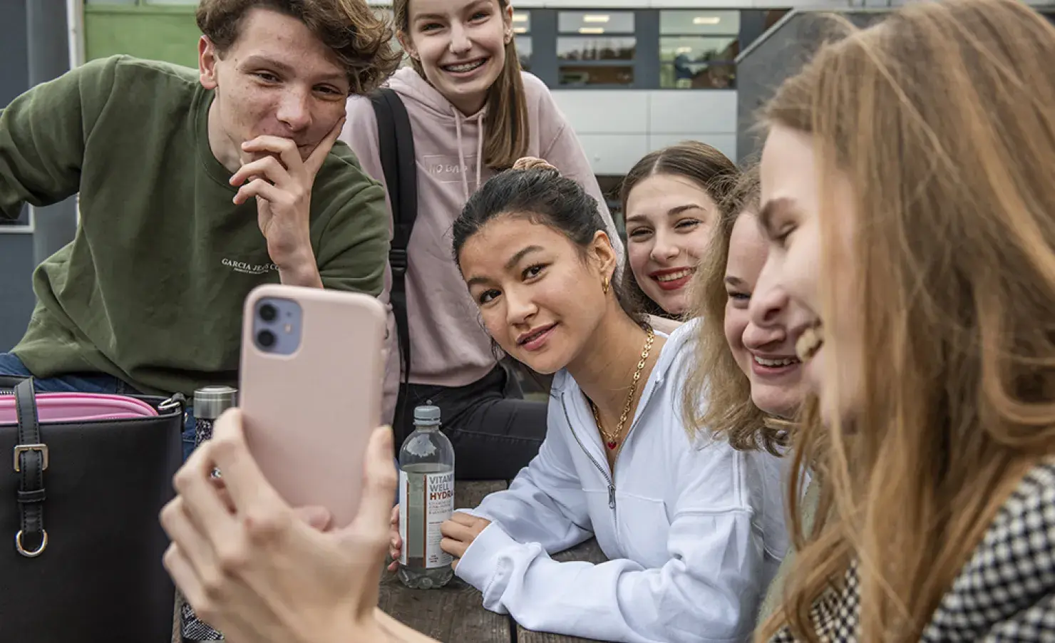 Groep studenten op schoolplein met telefoon