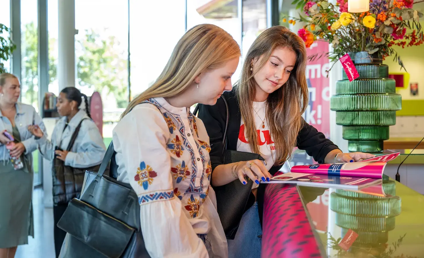 Studenten bij de receptie kijken in studiekeuzegids