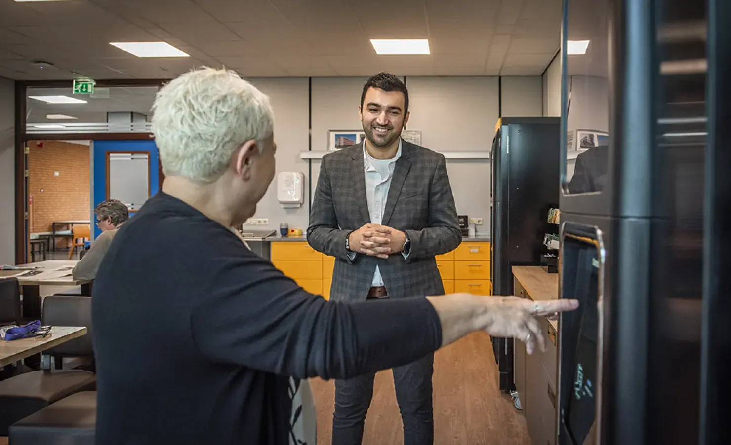 Twee collega's in de kantine bij de koffieautomaat