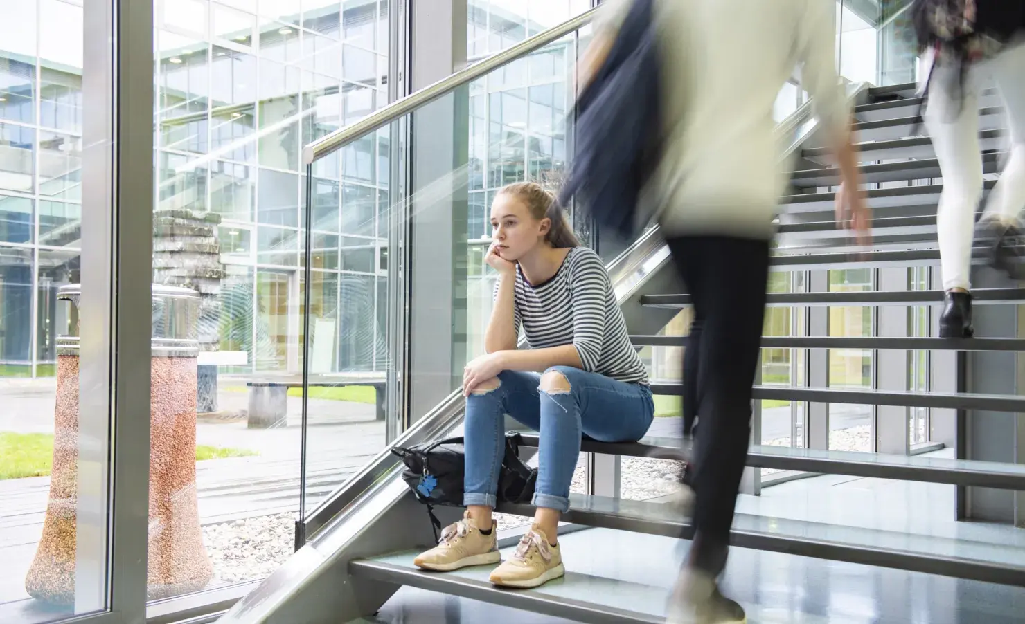 Bezorgde student op trap terwijl mensen voorbij razen