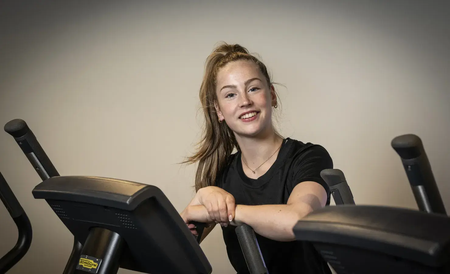 Meid leunend tegen een crosstrainer aan
