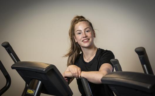 Meid leunend tegen een crosstrainer aan
