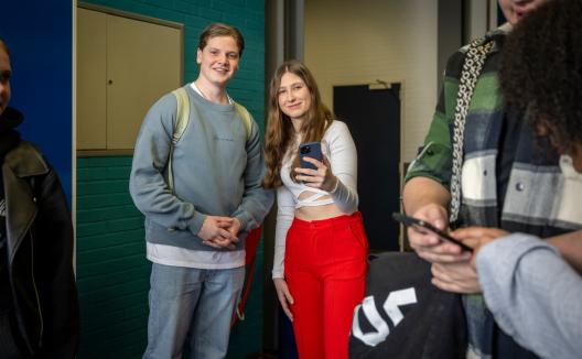 Studenten bij kluisjes met telefoon in hun handen