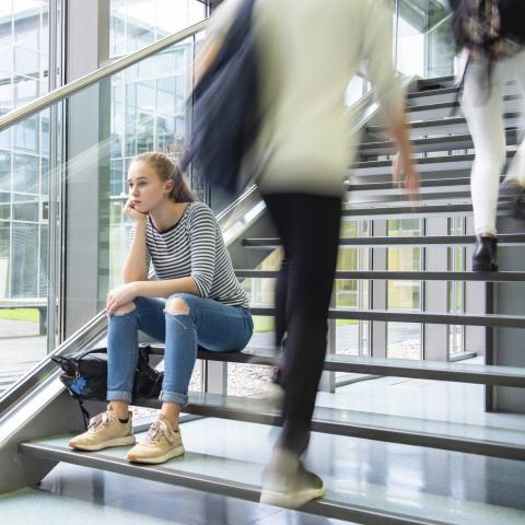 Bezorgde student op trap terwijl mensen voorbij razen