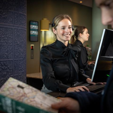 Medewerkster checkt hotelgast in