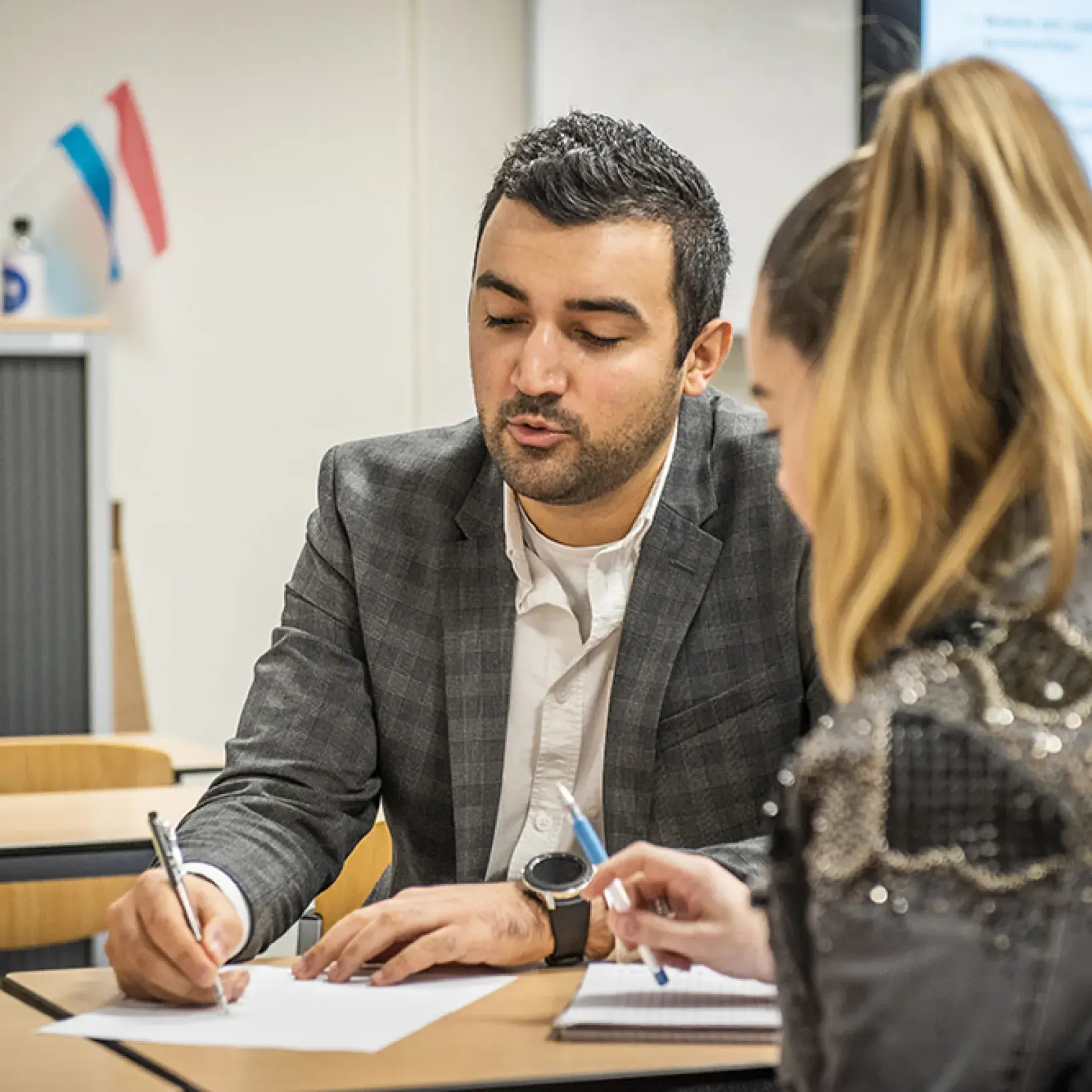 docent legt iets uit aan student
