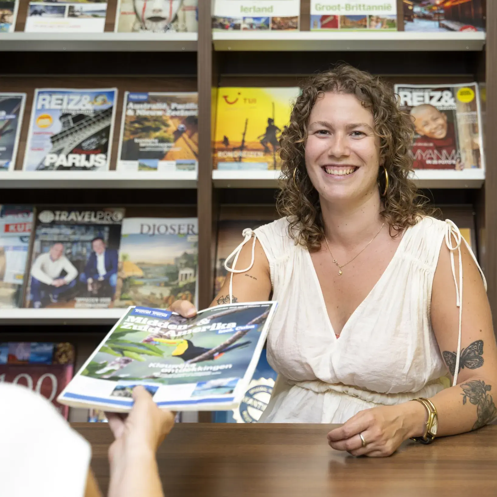 Dame bij reisbureau geeft brochure aan klant
