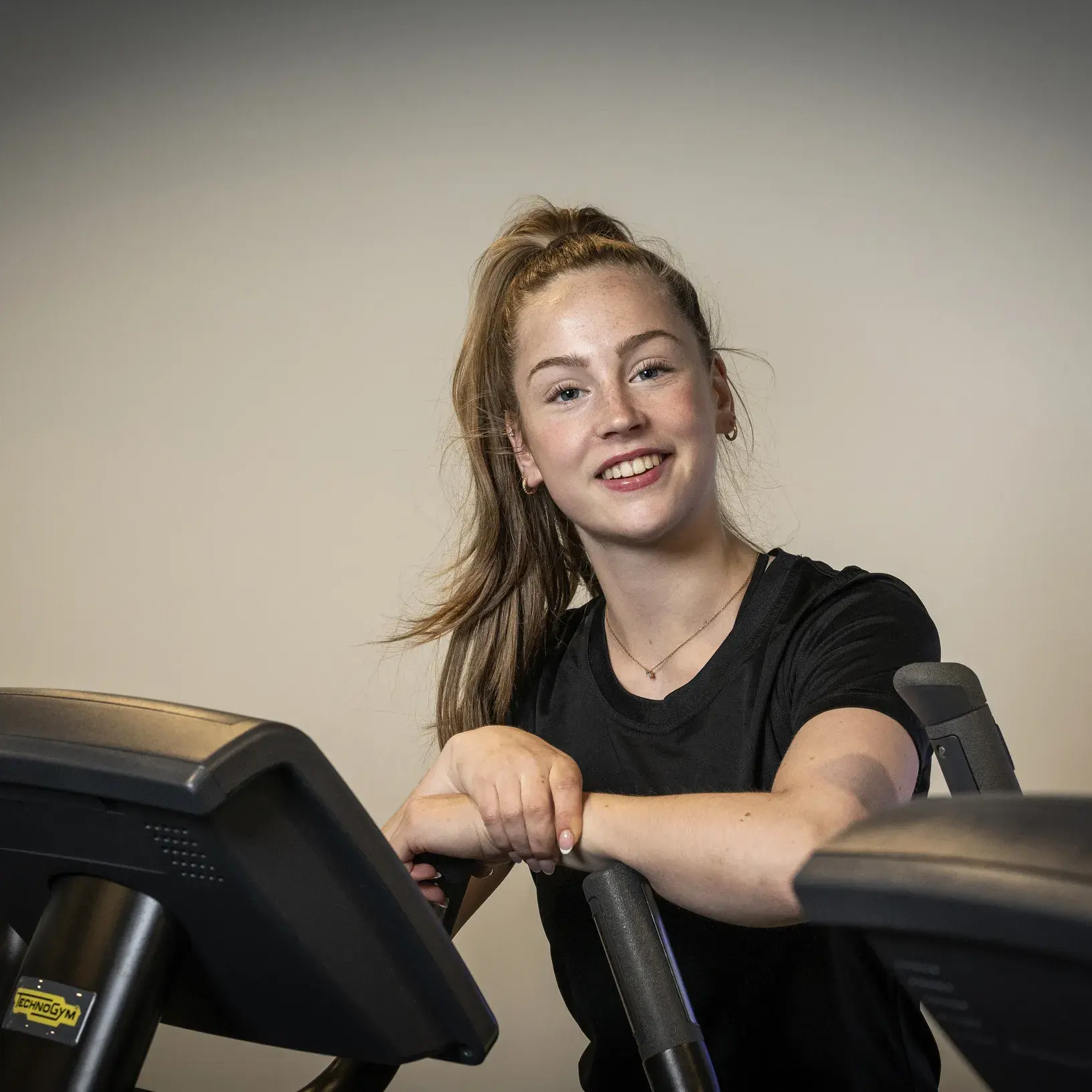 Meid leunend tegen een crosstrainer aan