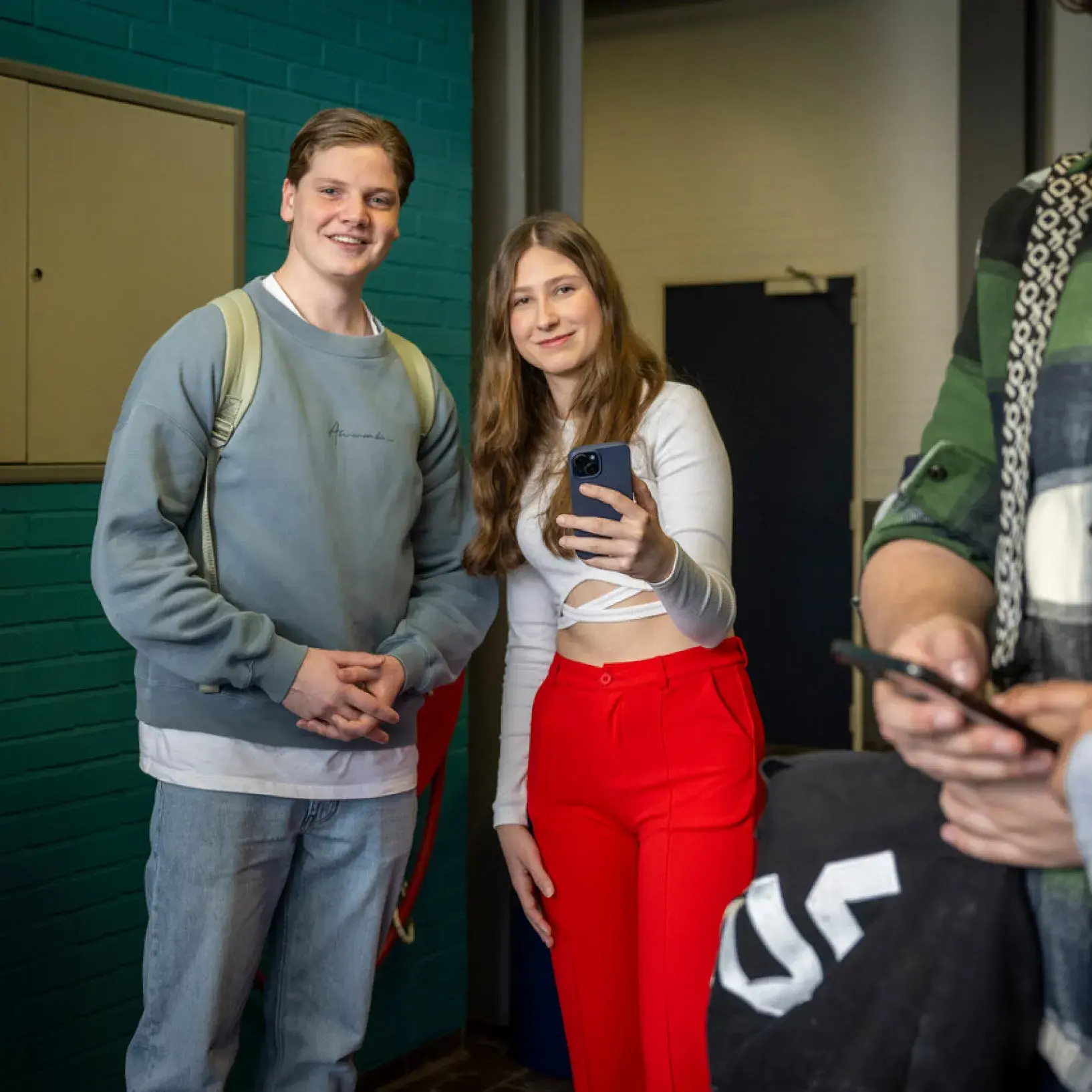 Studenten bij kluisjes met telefoon in hun handen